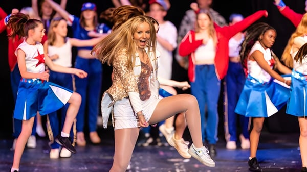 Eine Gruppe von Schülerinnen der Dauntsey’s School tritt auf einer Bühne mit bunten Outfits und auffälligen Frisuren auf.