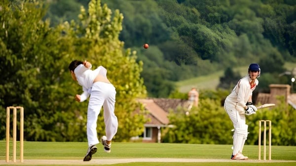 Zwei Cricketspieler in weißen Uniformen spielen ein Match auf dem grünen Spielfeld der Dauntsey’s School.