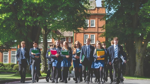 Eine Gruppe von Schülern steht vor einem historischen Backsteingebäude auf dem Campus der Dauntsey’s School.