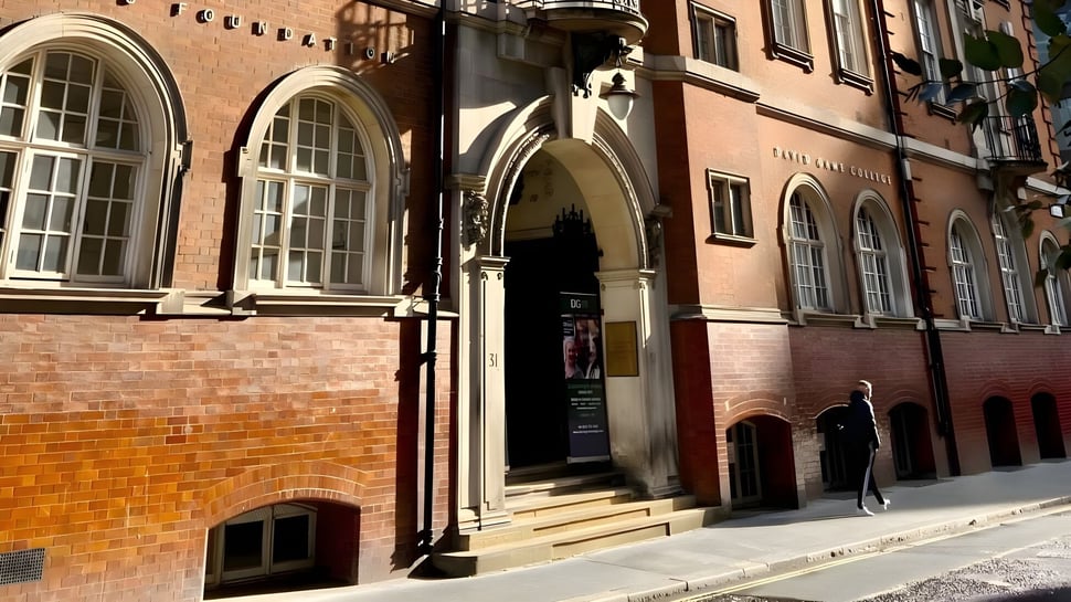 Das historische Backsteingebäude des David Game College Liverpool mit Rundbogenfenstern und kunstvoll gestalteter Eingangstür.