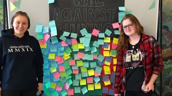 Zwei Schülerinnen stehen vor der Anti-Bullying-Wand mit bunten Notizen an der David Thompson Secondary School.