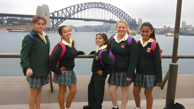 Eine Gruppe Schülerinnen der Davidson High School posiert vor der Sydney Harbour Bridge mit der Skyline der Stadt im Hintergrund.