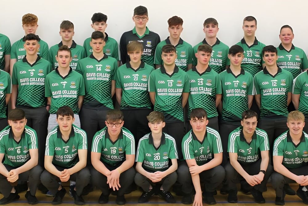 Eine Gruppe junger Athleten in grünen Trikots posiert auf dem Campus des Davis College vor weißem Hintergrund.