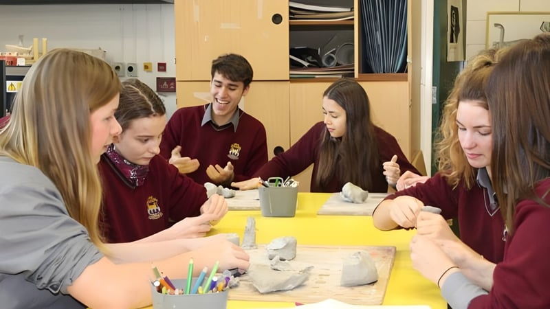 Schüler des Davis College arbeiten gemeinsam an einem Kunstprojekt mit verschiedenen Materialien an einem Tisch.