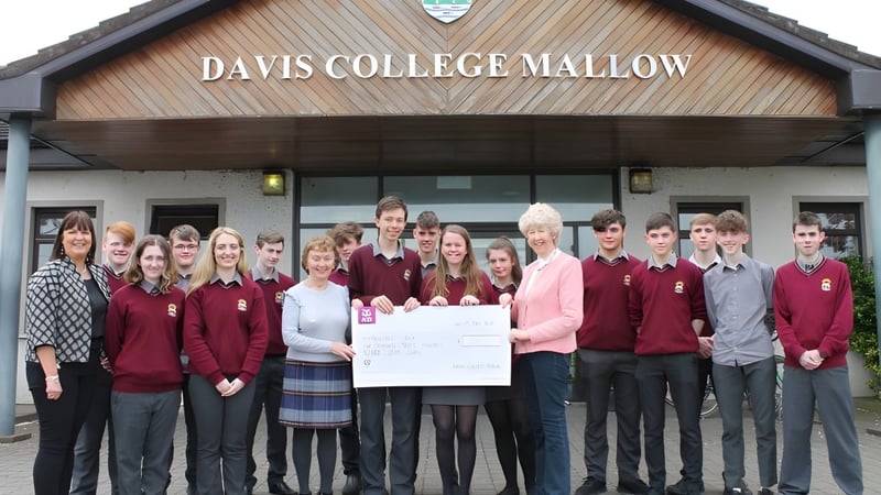 Schüler der Davis College stehen in Schuluniform vor dem Gebäude mit dem Schriftzug Davis College Mallow.