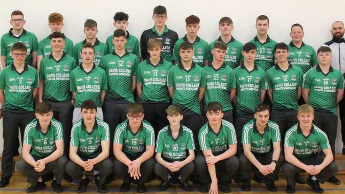 Eine Gruppe Schüler in grünen Uniformen posiert gemeinsam in einem Sportbereich auf dem Gelände des Davis College.