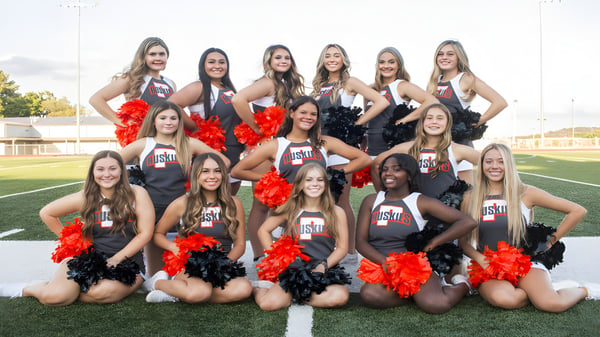 Eine Gruppe von Cheerleadern in einheitlichen Uniformen posiert auf dem Sportfeld im Davis School District.
