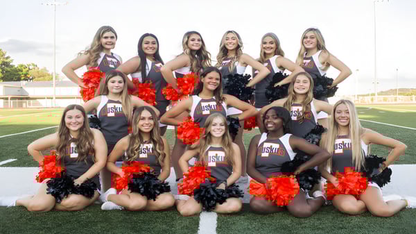 Eine Gruppe von Cheerleadern in einheitlichen Uniformen posiert auf dem Sportfeld im Davis School District.