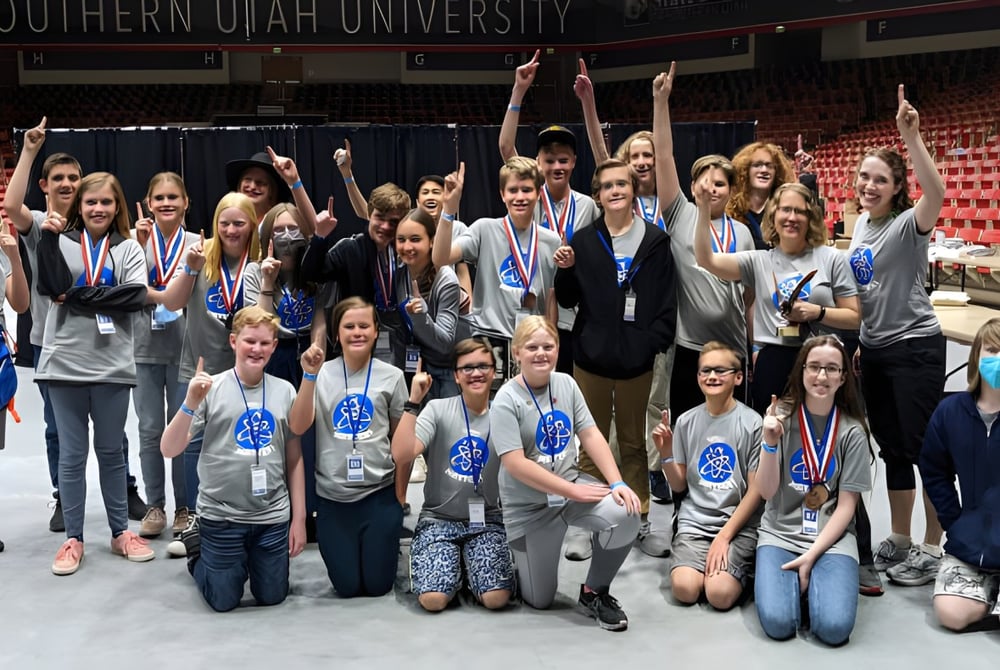 Eine Gruppe Schülerinnen und Schüler des Davis School District posiert gemeinsam in einer großen Halle mit Banner der Southern Utah University im Hintergrund.