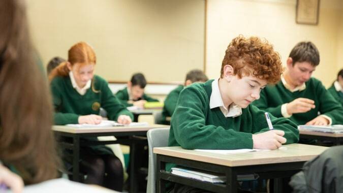 Schülerinnen und Schüler im grünen Schuluniform sitzen konzentriert im Klassenraum des Davitt College.