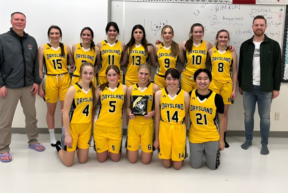 Eine Gruppe junger Basketballspielerinnen in gelben Trikots posiert zusammen mit ihren Trainern an der Daysland School.
