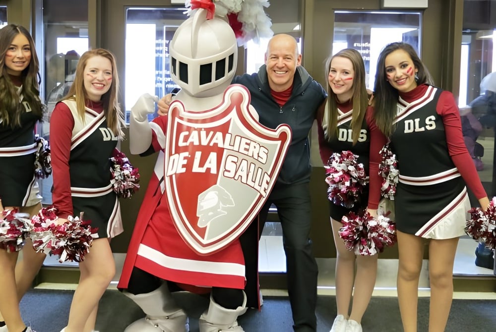 Cheerleader und das Maskottchen posieren gemeinsam in Rot-Schwarz auf dem Campus der École secondaire publique De La Salle.