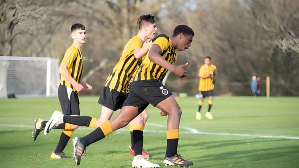 Schüler des De la Salle College Macroom spielen Fußball auf einem Spielfeld mit sichtbarem Tor.