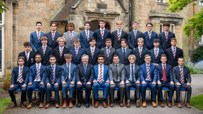 Schüler in Schuluniformen posieren vor einem historischen Steingebäude mit Turm auf dem Gelände des De la Salle College Macroom.