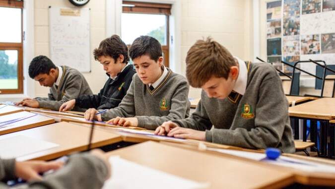 Schüler des De la Salle College in Churchtown sitzen in Uniformen im Klassenzimmer und arbeiten konzentriert an ihren Aufgaben.