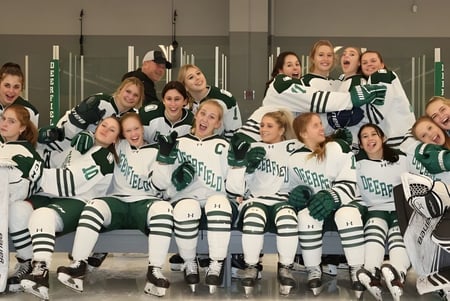 Eine Gruppe junger Schülerinnen in Hockey-Uniform posiert in einer Sportanlage auf dem Campus der Deerfield Academy.