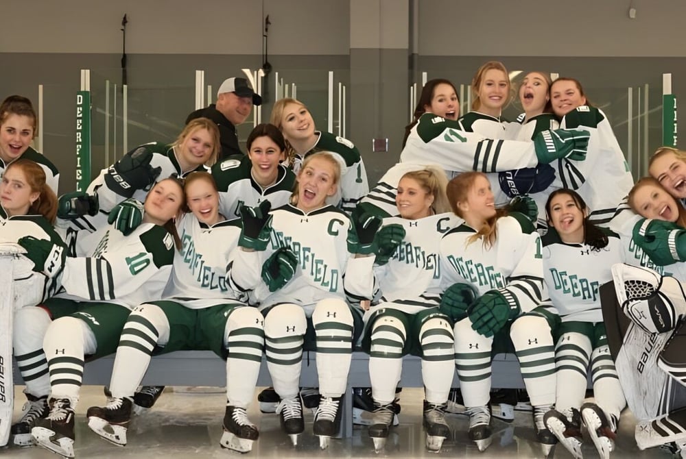 Eine Gruppe junger Schülerinnen in Hockey-Uniform posiert in einer Sportanlage auf dem Campus der Deerfield Academy.