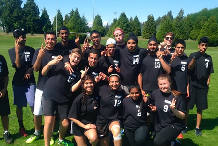 Eine Gruppe von Schülern der Delview Secondary School posiert gemeinsam auf einem Rasenplatz mit Bäumen im Hintergrund.