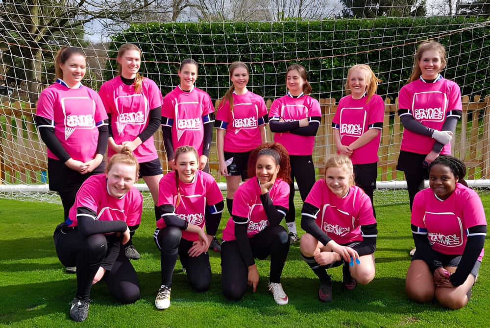 Eine Gruppe junger Fußballspielerinnen in pinken Trikots spielt auf dem Sportplatz der Denefield School.