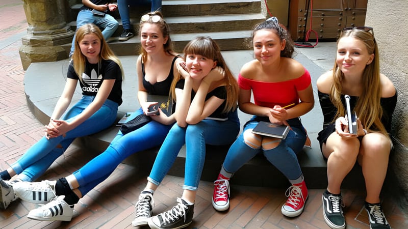 Eine Gruppe Schülerinnen sitzt auf den Stufen eines Gebäudes auf dem Campus der Denefield School und unterhält sich miteinander.