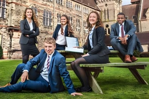 Eine Gruppe von Schülerinnen und Schülern des Denstone College posiert auf einer Rasenfläche vor einem historischen Gebäude.