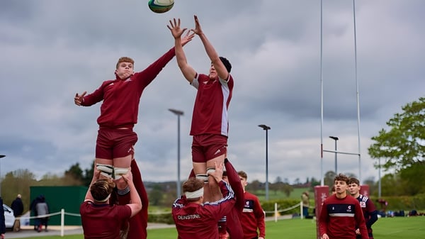 Zwei Schülerinnen in roten Trikots springen beim Sportunterricht am Denstone College nach einem Ball.