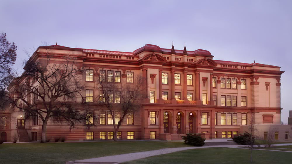Gebaeude mit detailreicher Architektur auf dem Gelaende des Denver Public School District umgeben von Gras und Baeumen.