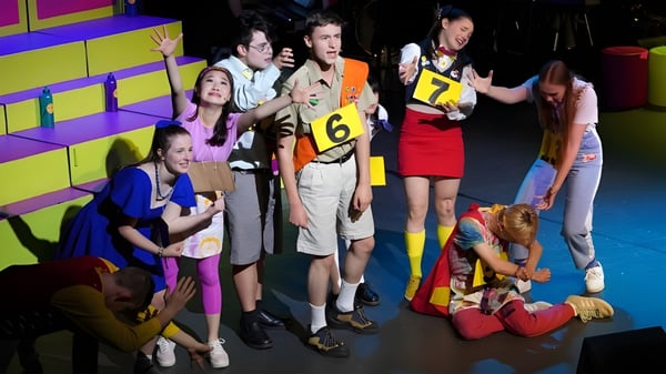 Eine Gruppe von Schülerinnen und Schülern des Dickson College versammelt sich im hinteren Bühnenbereich mit bunter Kulisse.