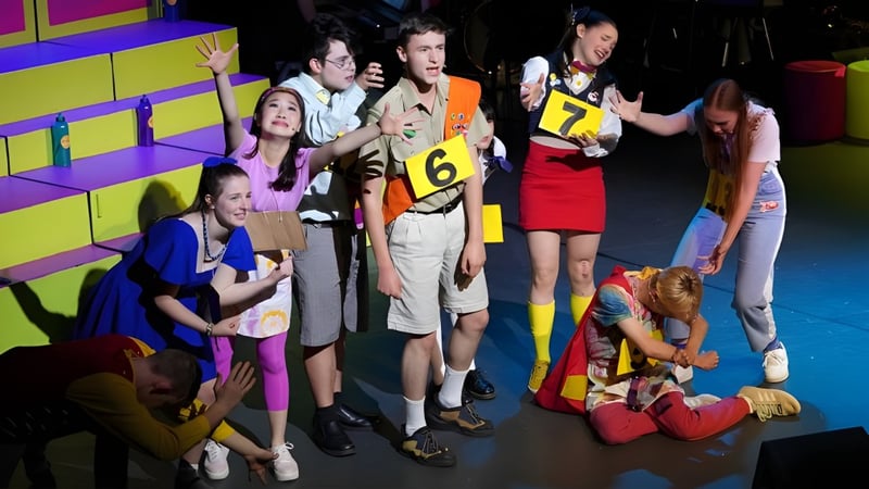 Eine Gruppe von Schülerinnen und Schülern des Dickson College versammelt sich im hinteren Bühnenbereich mit bunter Kulisse.