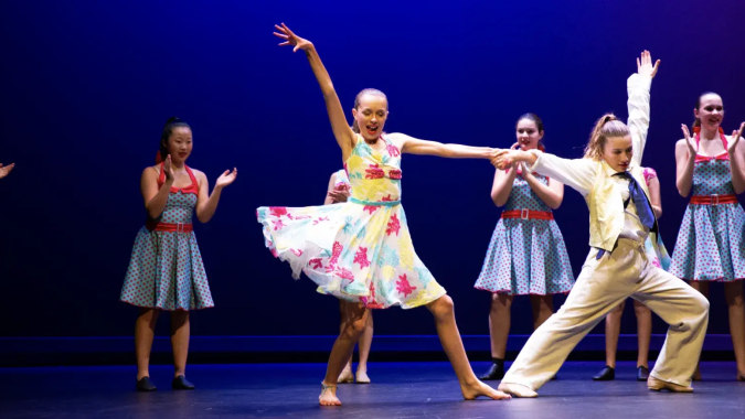 Schülerinnen der Diocesan School For Girls führen eine Tanzperformance auf der Bühne mit bunten Kostümen vor.