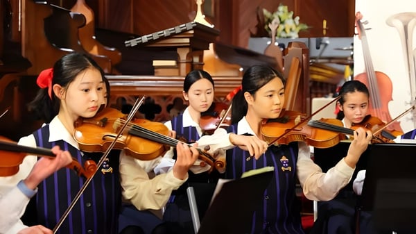 Schülerinnen der Diocesan School For Girls spielen gemeinsam Geigen in einem Musikraum.