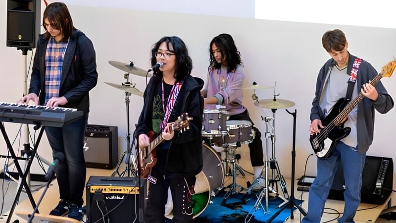 Eine Gruppe Musiker tritt auf der Bühne des DLD College London mit verschiedenen Instrumenten und Equipment auf.