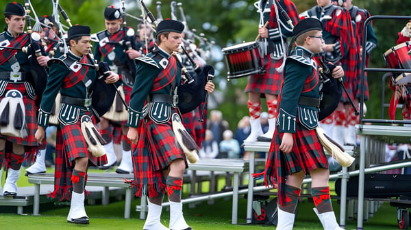 Männer in traditionellen schottischen Kilts und Uniformen mit Dudelsäcken und Trommeln bei einem Umzug auf dem Gelände der Dollar Academy.
