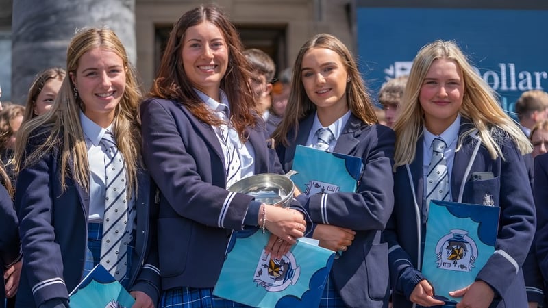 Eine Gruppe junger Schülerinnen in Schuluniformen steht zusammen auf dem Campus der Dollar Academy.
