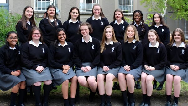 Eine Gruppe Schülerinnen des Dominican College Sion Hill steht vor einem Gebäude mit großen Fenstern.