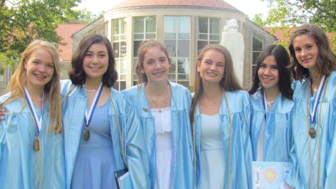 Eine Gruppe junger Frauen im blauen Abschlussgewand steht vor einem Gebäude mit Kuppeldach auf dem Campus des Dominican College in Wicklow.