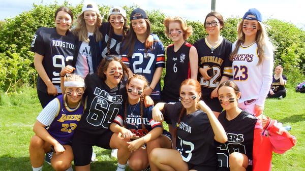 Eine Gruppe junger Schülerinnen des Dominican College Wicklow steht im Freien auf einer Wiese zusammen.