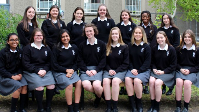 Eine Gruppe von Schülerinnen in Schuluniformen steht vor einem Gebäude auf dem Campus des Dominican College Sion Hill.