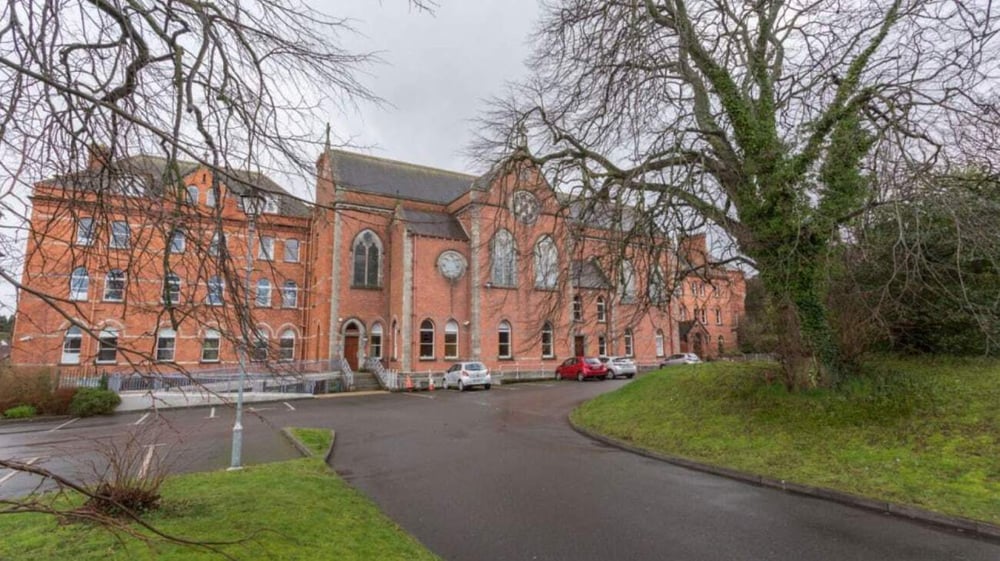 Das große Backsteingebäude mit Uhrenturm auf dem Campus des Dominican College Wicklow steht vor kahlen Bäumen und einem gepflasterten Weg.