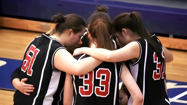 Eine Gruppe junger Basketballspielerinnen steht eng umarmt auf dem Spielfeld der Dominion Academy of Dayton.