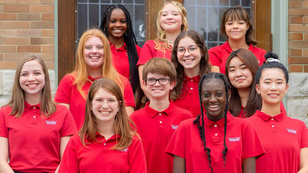 Eine Gruppe Schülerinnen der Dominion Academy of Dayton posiert lächelnd vor einem Backsteingebäude.