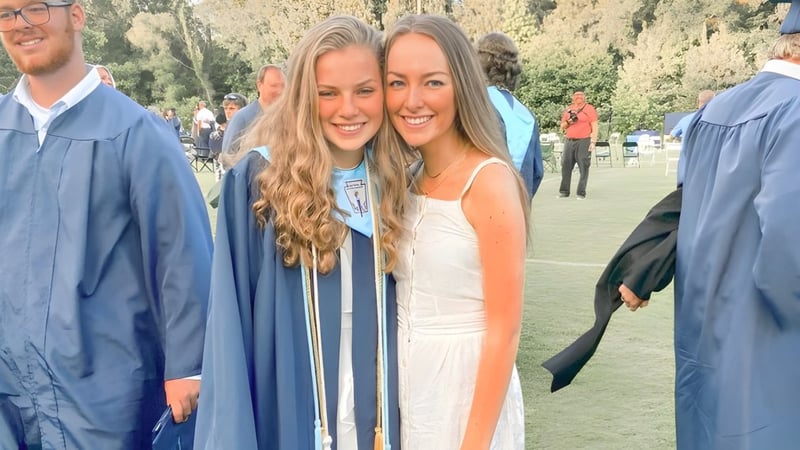 Zwei Schülerinnen der Dominion Christian School stehen im Studienabschlussgewand auf einer Wiese.