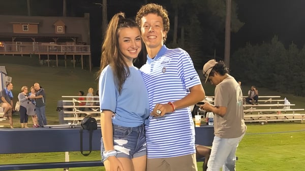 Ein junges Paar umarmt sich und lächelt auf dem Sportfeld der Dominion Christian School.