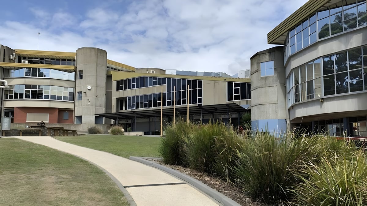 Das moderne mehrstöckige Gebäude des Don College mit großen Fenstern und einer Rasenfläche im Vordergrund.
