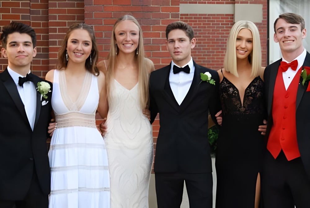 Eine Gruppe gut gekleideter Personen, darunter ein Paar in formeller Kleidung, posiert vor einem Backsteingebäude auf dem Campus des Don College.