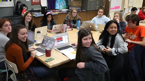 Eine Gruppe Schüler des Don College arbeitet gemeinsam mit Laptops an einem Tisch im Klassenraum.
