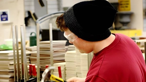 Eine Person mit rotem Hemd und schwarzem Hut steht in einem Raum mit vielen Kartons im Don Mills Collegiate Institute.