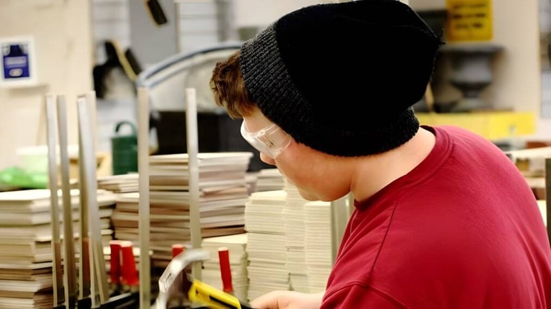 Eine Person mit rotem Hemd und schwarzem Hut steht in einem Raum mit vielen Kartons im Don Mills Collegiate Institute.