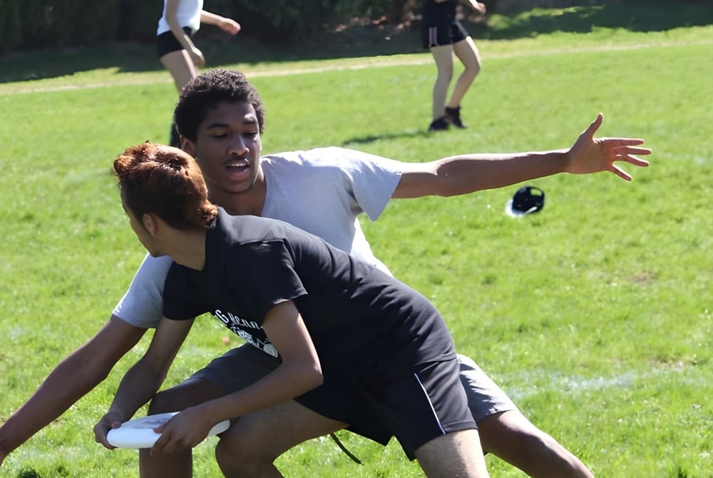 Auf einem Rasenfeld des Don Mills Collegiate Institute kämpfen ein Mann und eine Frau körperlich miteinander.