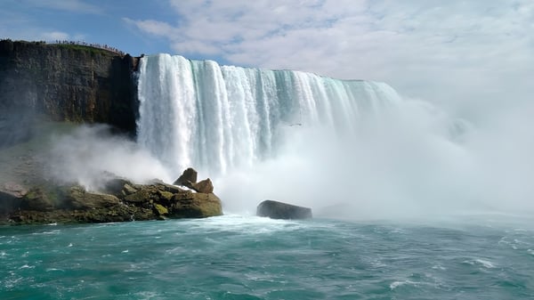 Ein Wasserfall fließt über einen Felsen mit der umliegenden Landschaft im Hintergrund auf dem Gelände des Don Mills Collegiate Institute.